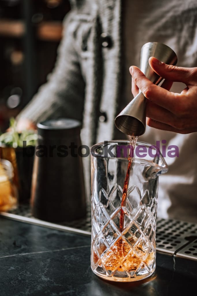 Bartender Pouring Spirit In To Mixing Glass Black Bar Top