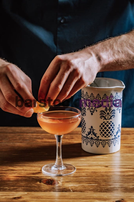 Bartender Garnishing Coupe on a Wood Bar Top