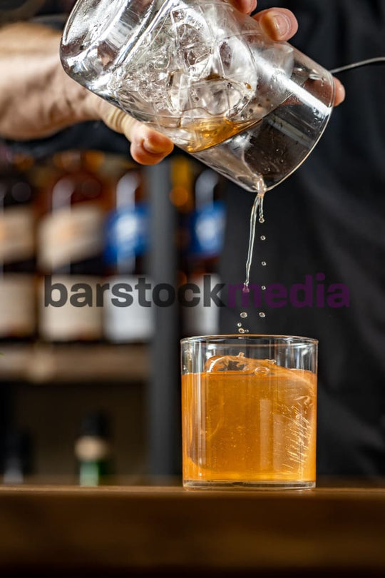 Stirred Cocktail Being Poured Over Clear Ice